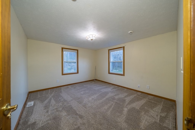 carpeted empty room with a textured ceiling