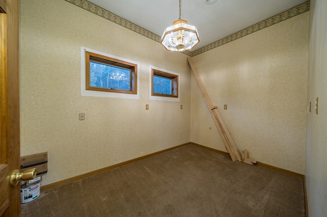 carpeted empty room with a chandelier