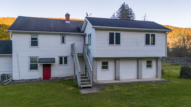 rear view of house featuring a lawn and central air condition unit