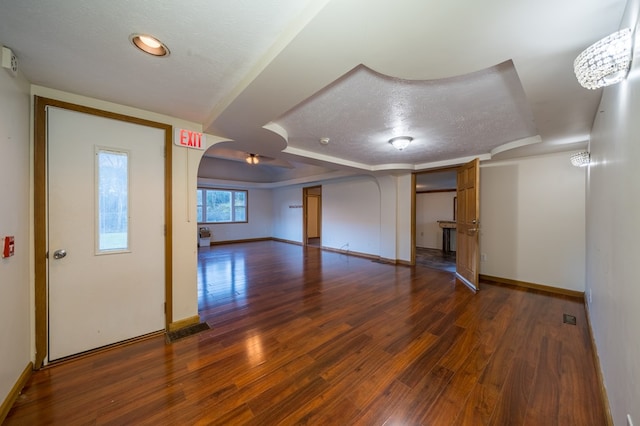 interior space featuring a notable chandelier, dark hardwood / wood-style floors, a textured ceiling, and a tray ceiling