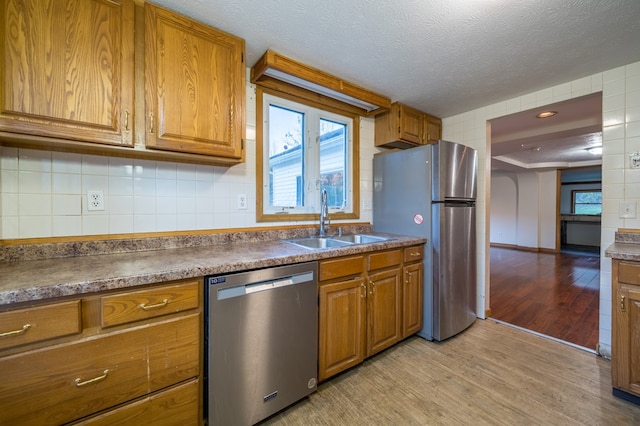 kitchen with light wood-type flooring, tasteful backsplash, a textured ceiling, stainless steel appliances, and sink