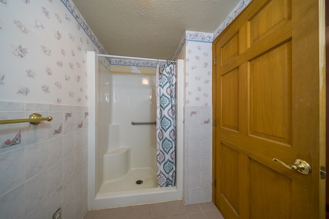 bathroom featuring tile patterned floors, tile walls, a textured ceiling, and walk in shower