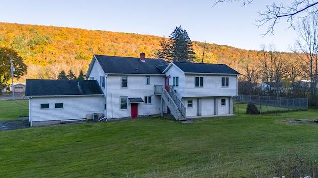 rear view of house featuring cooling unit and a yard