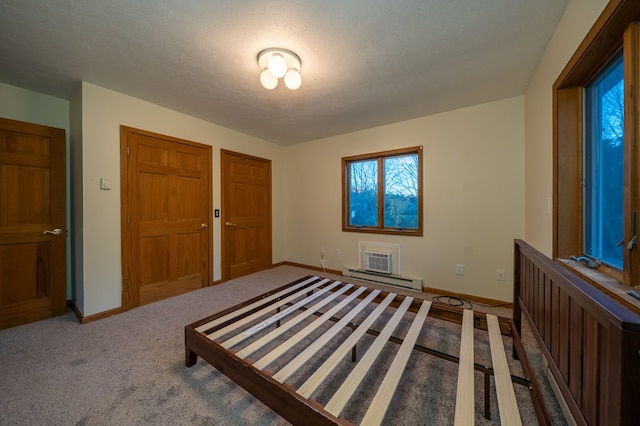 unfurnished bedroom featuring carpet flooring, a textured ceiling, and a baseboard heating unit