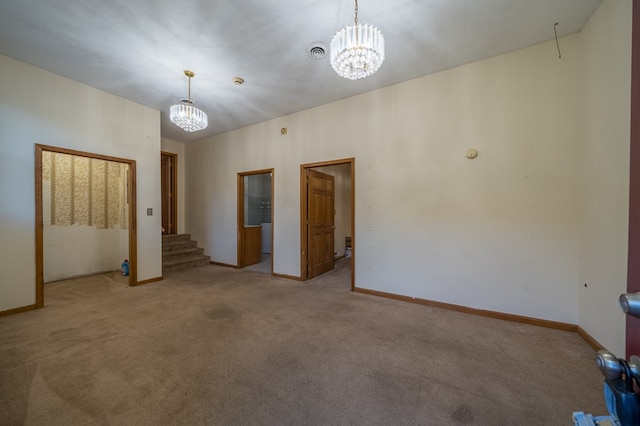 spare room featuring a notable chandelier and light carpet