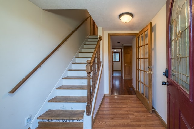 staircase with hardwood / wood-style floors and a textured ceiling