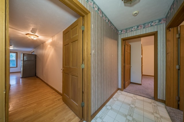 hallway with light wood-type flooring and a textured ceiling