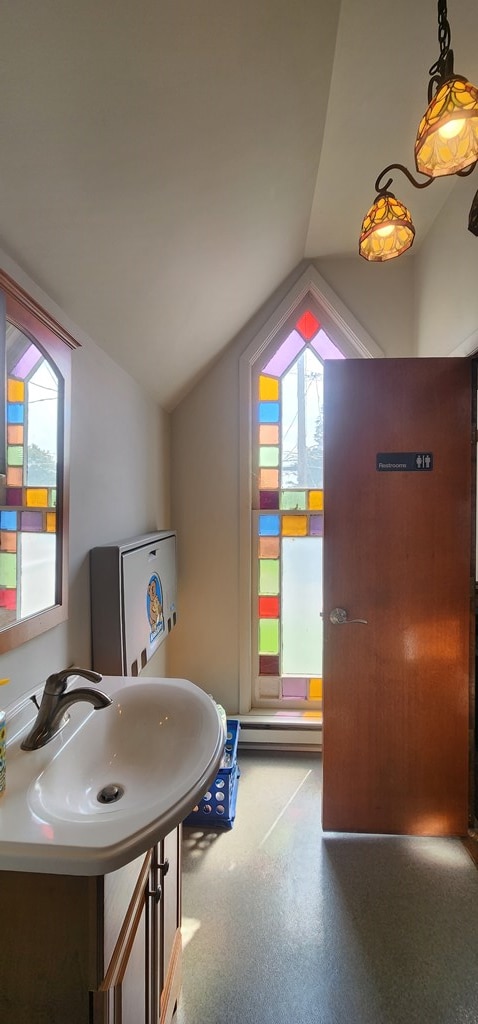 bathroom featuring a healthy amount of sunlight, lofted ceiling, and sink