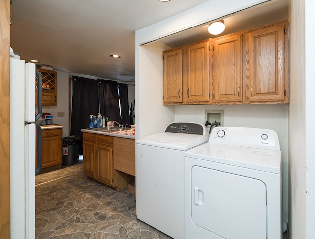 laundry room featuring laundry area, stone finish floor, independent washer and dryer, and a sink