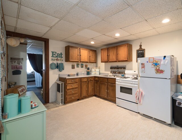 kitchen featuring white appliances, brown cabinetry, light countertops, a paneled ceiling, and recessed lighting