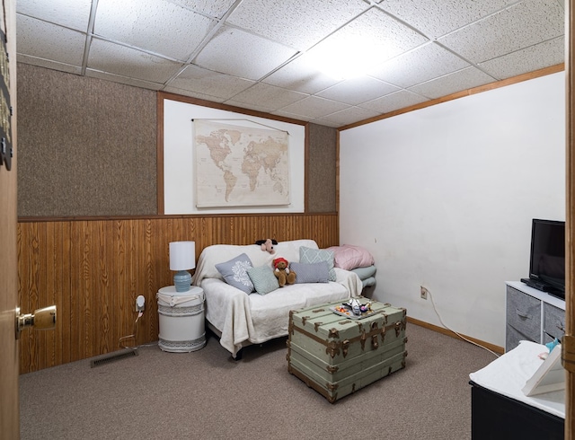 bedroom featuring a paneled ceiling, visible vents, wainscoting, carpet flooring, and wooden walls