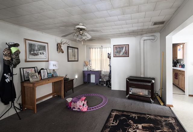 interior space with ceiling fan, a wood stove, and visible vents