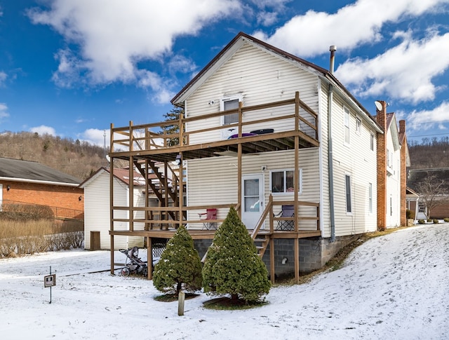 snow covered rear of property featuring stairway and a wooden deck