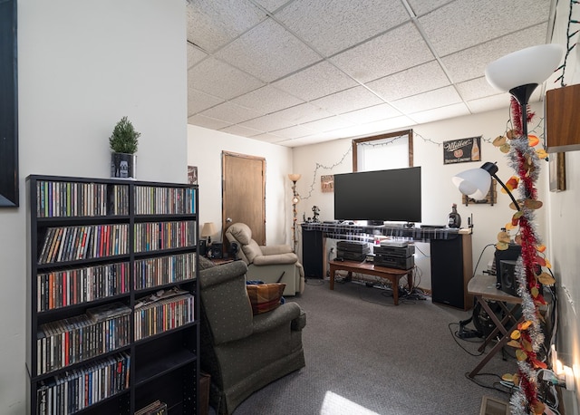 carpeted living area with a paneled ceiling