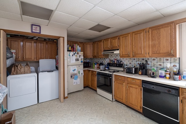 kitchen with brown cabinets, light countertops, independent washer and dryer, under cabinet range hood, and black appliances