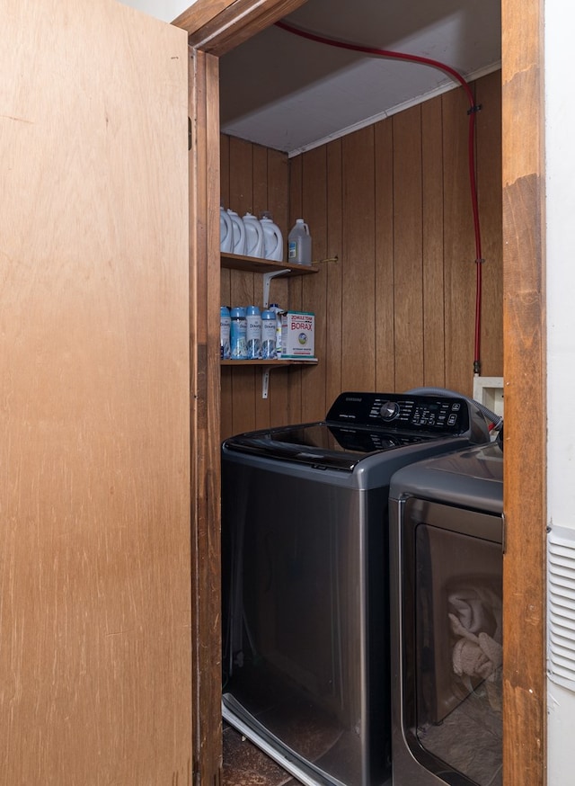 laundry area with laundry area, wood walls, and independent washer and dryer