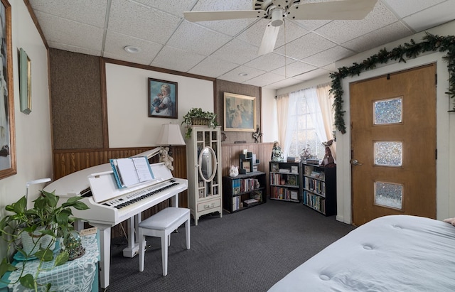 bedroom featuring a paneled ceiling, a wainscoted wall, and dark carpet