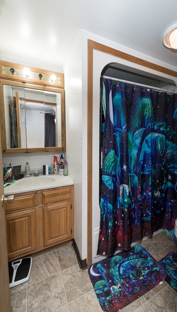 bathroom featuring stone finish flooring, baseboards, and vanity