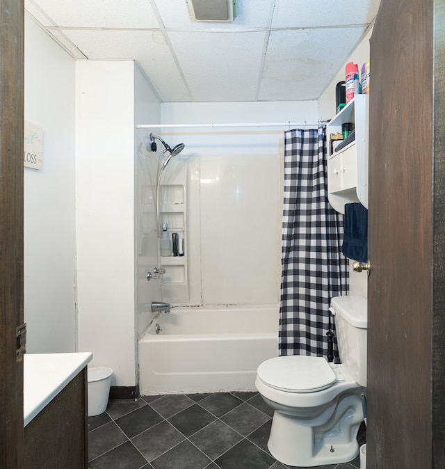 bathroom with a drop ceiling, toilet, tile patterned floors, vanity, and shower / tub combo with curtain