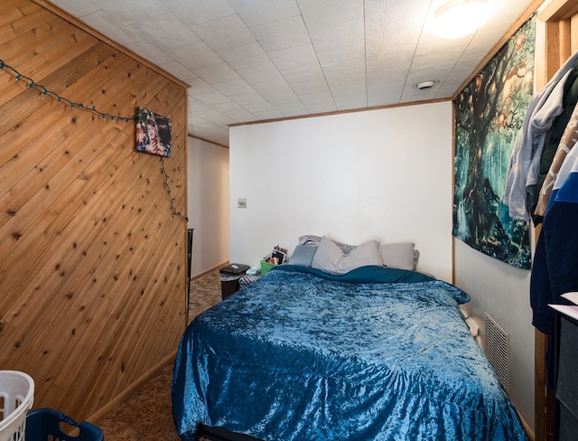 bedroom with wood walls, carpet flooring, and visible vents