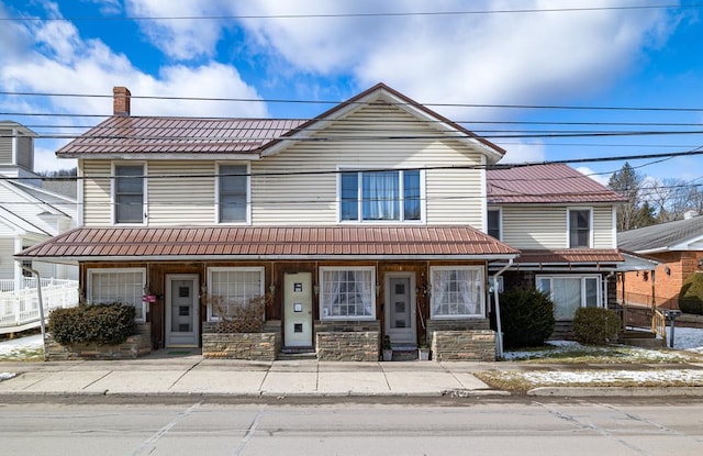 view of front of house featuring a garage, stone siding, a tile roof, and a chimney