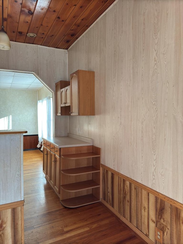 corridor with wood walls, light hardwood / wood-style floors, and wooden ceiling