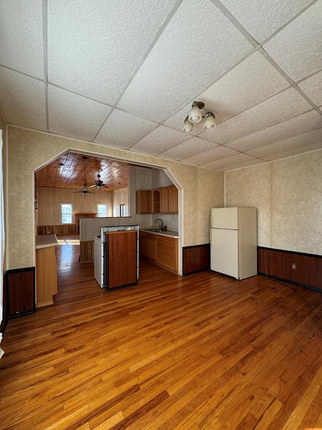 kitchen with ceiling fan, hardwood / wood-style floors, kitchen peninsula, and white fridge