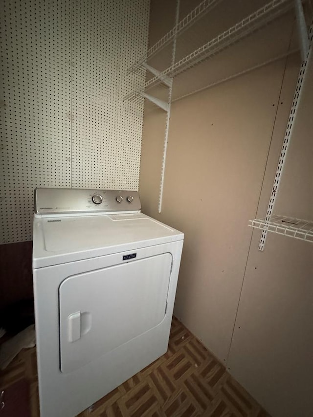 washroom with parquet flooring and washer / dryer