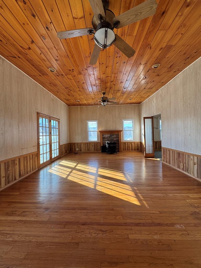 unfurnished living room featuring ceiling fan, wood ceiling, a fireplace, and hardwood / wood-style flooring