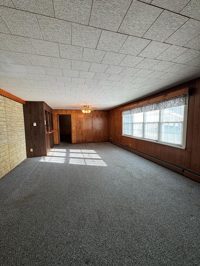 empty room with baseboard heating, carpet floors, and wooden walls