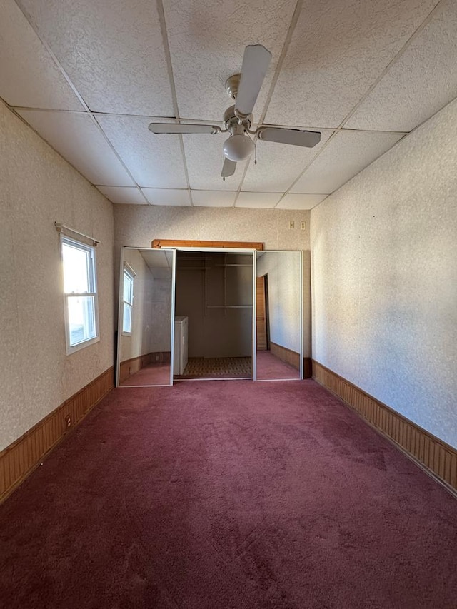 unfurnished bedroom featuring a paneled ceiling, carpet, a closet, and ceiling fan