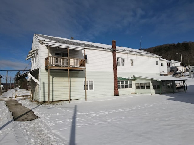 snow covered rear of property with a balcony