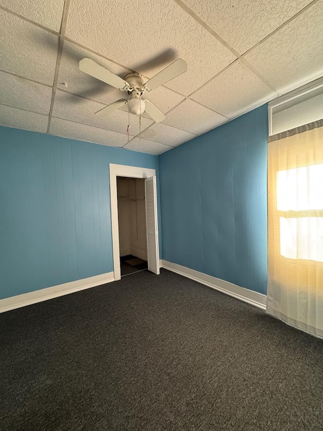 unfurnished room with ceiling fan and dark carpet