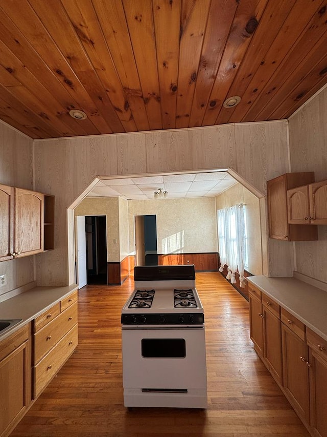 kitchen with wooden ceiling, light hardwood / wood-style floors, white range with gas stovetop, and wooden walls