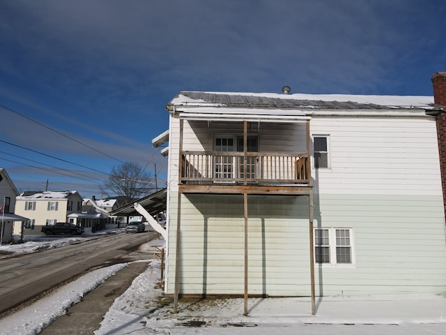 snow covered rear of property with a balcony and a garage