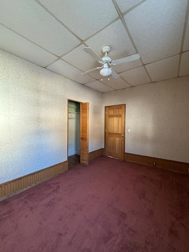 empty room with ceiling fan, a paneled ceiling, and carpet floors