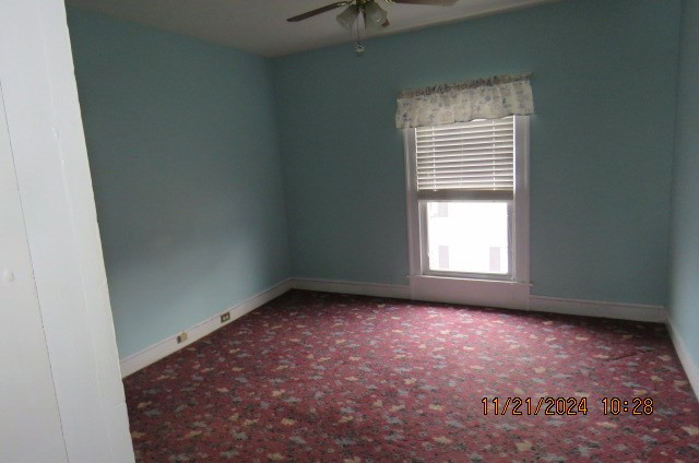 carpeted empty room featuring ceiling fan