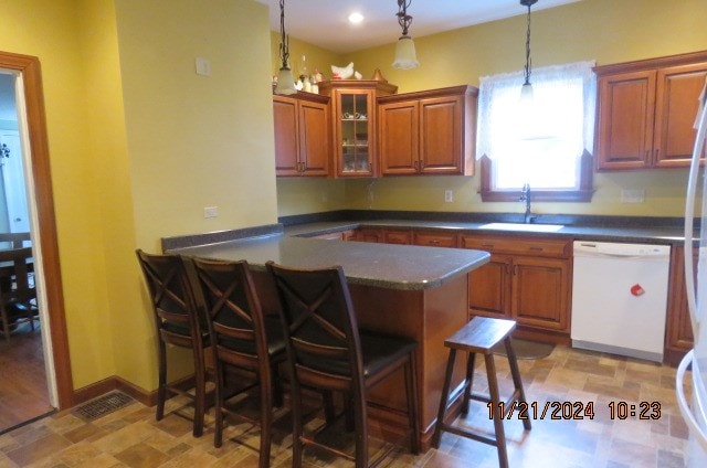 kitchen with a kitchen bar, kitchen peninsula, dishwasher, and sink