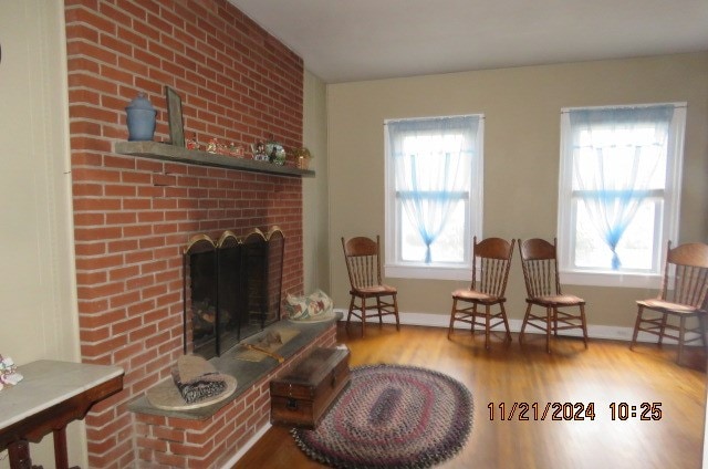 sitting room featuring wood-type flooring and a brick fireplace