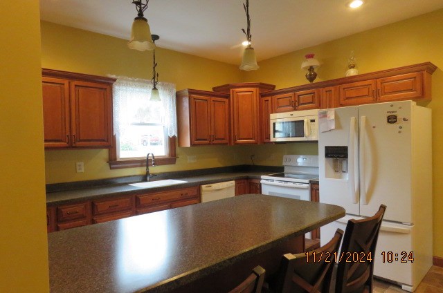 kitchen featuring sink, decorative light fixtures, and white appliances