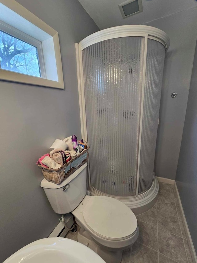 bathroom featuring baseboards, toilet, a shower stall, and tile patterned flooring