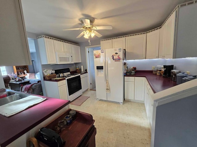 kitchen with a ceiling fan, dark countertops, white appliances, white cabinets, and light floors