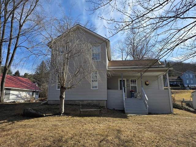 rear view of house featuring a yard and a porch