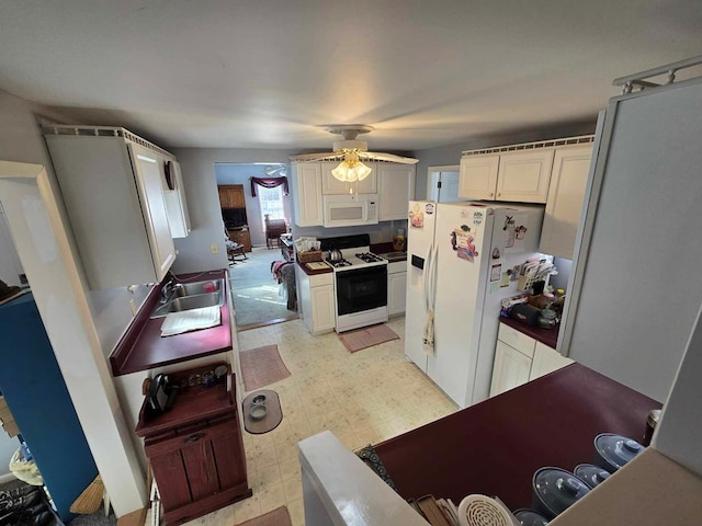 kitchen with a sink, white appliances, light floors, and ceiling fan