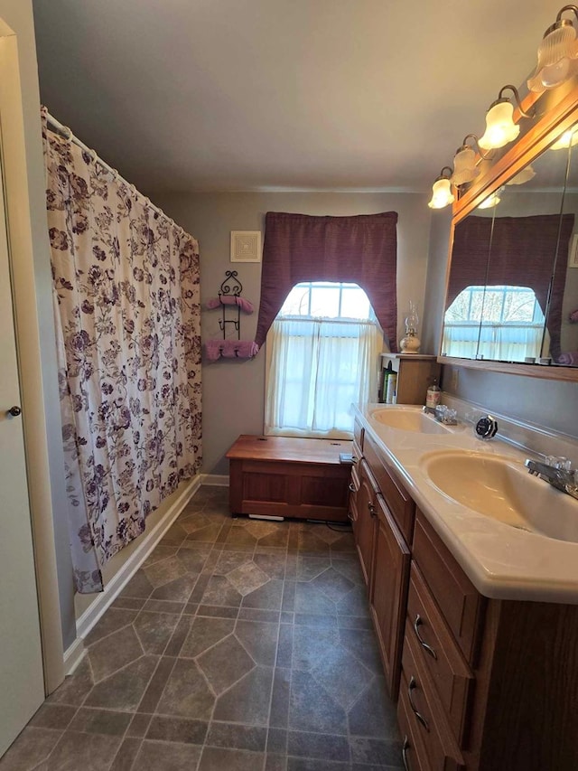 bathroom with a sink, a shower with curtain, an inviting chandelier, and double vanity