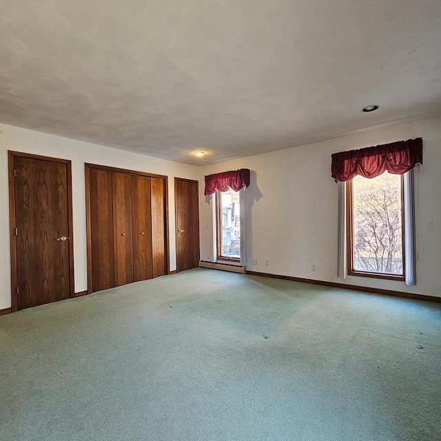 carpeted empty room with a baseboard heating unit