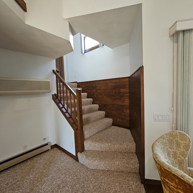 stairs with a baseboard heating unit and carpet