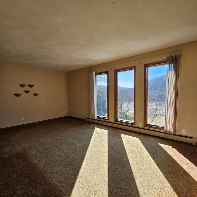 carpeted empty room with a baseboard heating unit and a mountain view