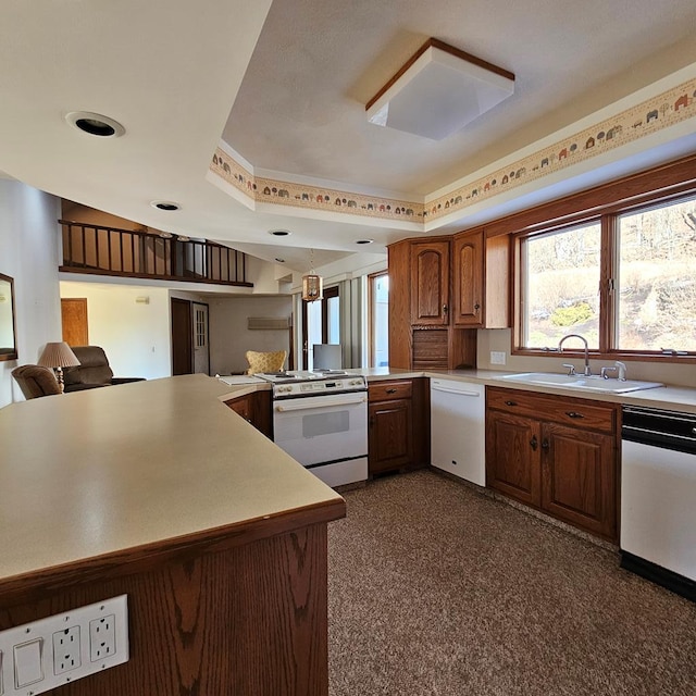 kitchen featuring white appliances, kitchen peninsula, sink, and hanging light fixtures