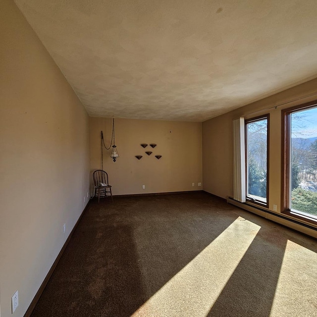 spare room featuring dark carpet and baseboard heating